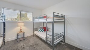 A bunk bed room with a window, a lamp, and a small table. - Spacious Vegas Retreat • Close to Strip • Sleep 12 (Las Vegas)