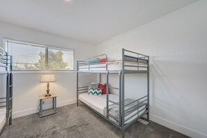 A bunk bed room with a window, a lamp, and a small table. - Spacious Vegas Retreat • Close to Strip • Sleep 12 (Las Vegas)