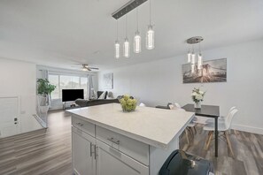 A modern kitchen with a large island, pendant lights, and a dining area with white chairs. - Spacious Vegas Retreat • Close to Strip • Sleep 12 (Las Vegas)