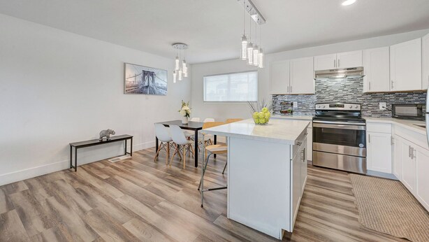 A modern kitchen with white cabinetry, a central island, stainless steel appliances, and a hanging light fixture. - Spacious Vegas Retreat • Close to Strip • Sleep 12 (Las Vegas)