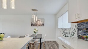 A modern kitchen with a central island, pendant lighting, and a dining area with a table and chairs. - Spacious Vegas Retreat • Close to Strip • Sleep 12 (Las Vegas)
