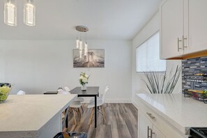 A modern kitchen with a central island, pendant lighting, and a dining area with a table and chairs. - Spacious Vegas Retreat • Close to Strip • Sleep 12 (Las Vegas)