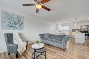 A modern living room with a grey sofa, a small round table, and a ceiling fan. - Spacious Vegas Retreat • Close to Strip • Sleep 12 (Las Vegas)