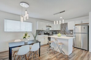 A modern kitchen with white cabinetry, a central island, stainless steel appliances, and pendant lighting. - Spacious Vegas Retreat • Close to Strip • Sleep 12 (Las Vegas)