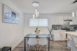 A modern kitchen with white cabinets, a black stove, and a backsplash with black and white tiles. - Spacious Vegas Retreat • Close to Strip • Sleep 12 (Las Vegas)