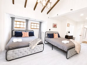 Ein Schlafzimmer mit zwei Betten, einer Chandelüster und einer Tür.