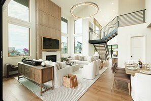 Un vaste salon doté d’une cheminée, d’un escalier et d’un coin repas avec une table mise pour le repas.