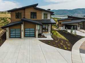 A modern two-story house with a garage, a stone facade, and a landscaped driveway.
