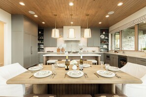 Une cuisine moderne dotée d’un îlot central, de luminaires suspendus et d’un coin repas aménagé pour accueillir six personnes.