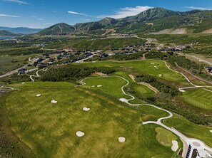 En golfbana med flera hål, ett bostadsområde med hus och en bergig bakgrund.