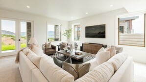 A modern living room with a large sofa, a coffee table, and a television. - NEW Luxury Retreat in Deer Valley East, Free Ski Shuttle, Hot Tub, Sleeps 18 (Heber City)