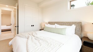 A bedroom with a large bed, a bedside table with a lamp, a door, and a window. - NEW Luxury Retreat in Deer Valley East, Free Ski Shuttle, Hot Tub, Sleeps 18 (Heber City)