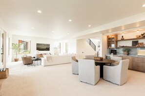 A spacious living room with a dining area, a kitchen, and a staircase leading to an upper level.