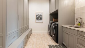 A laundry room with a washing machine, a dryer, and a sink with a mirror. - NEW Luxury Retreat in Deer Valley East, Free Ski Shuttle, Hot Tub, Sleeps 18 (Heber City)