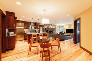 A modern kitchen with wooden cabinets, a stainless steel refrigerator, and a stone fireplace. - Historic Old Town 2BR/2BA condo with mountain views. (Park City)