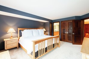 Um quarto com cama de madeira, mesa de cabeceira, luminária e guarda-roupa.