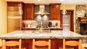 Eine Küche mit Granit Arbeitsplatten, Holzschränken, einem Edelstahl-Kühlschrank und Pendelleuchten.