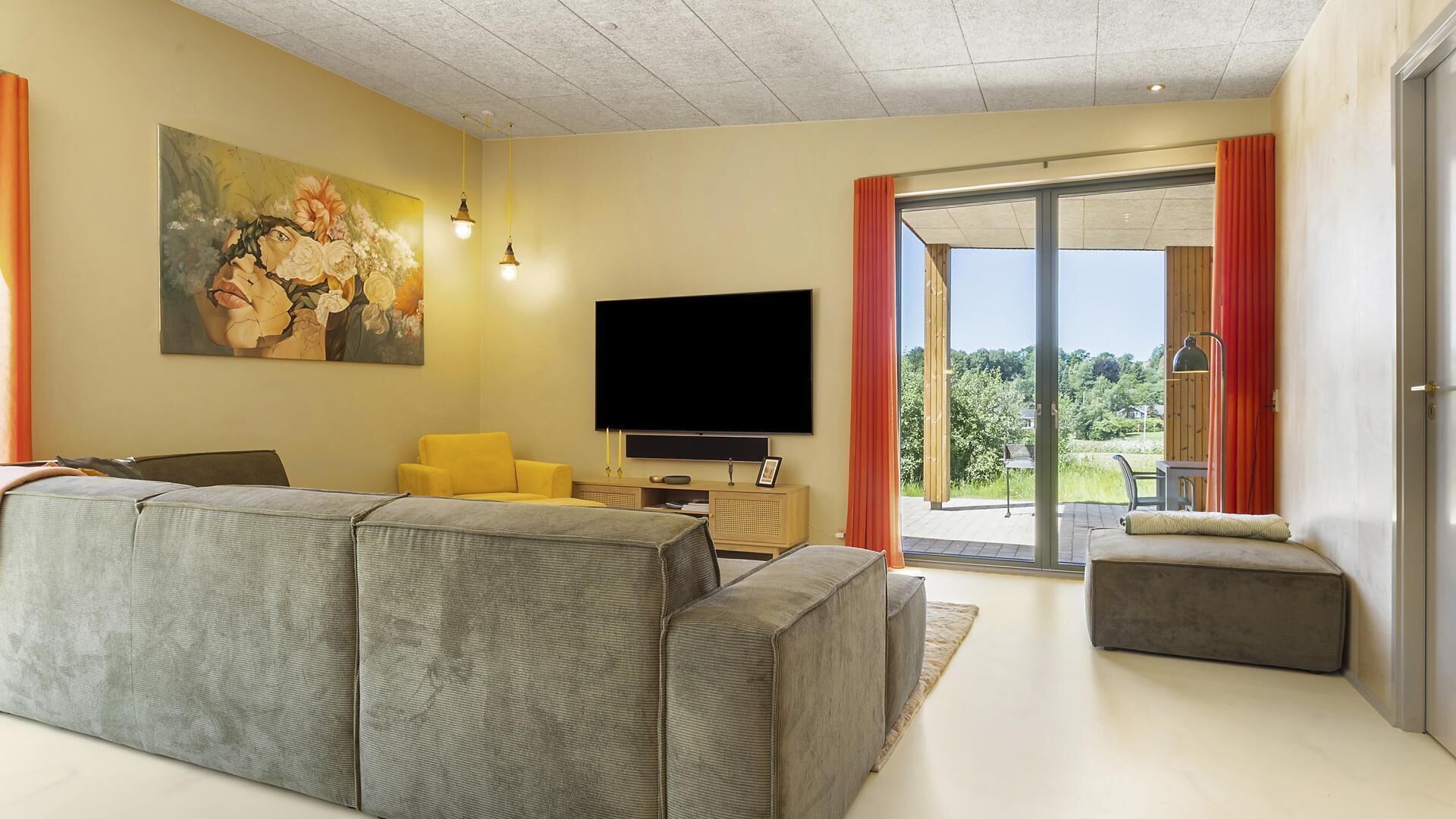 A modern living room with a grey sofa, a yellow armchair, a flat-screen TV, and a painting on the wall.