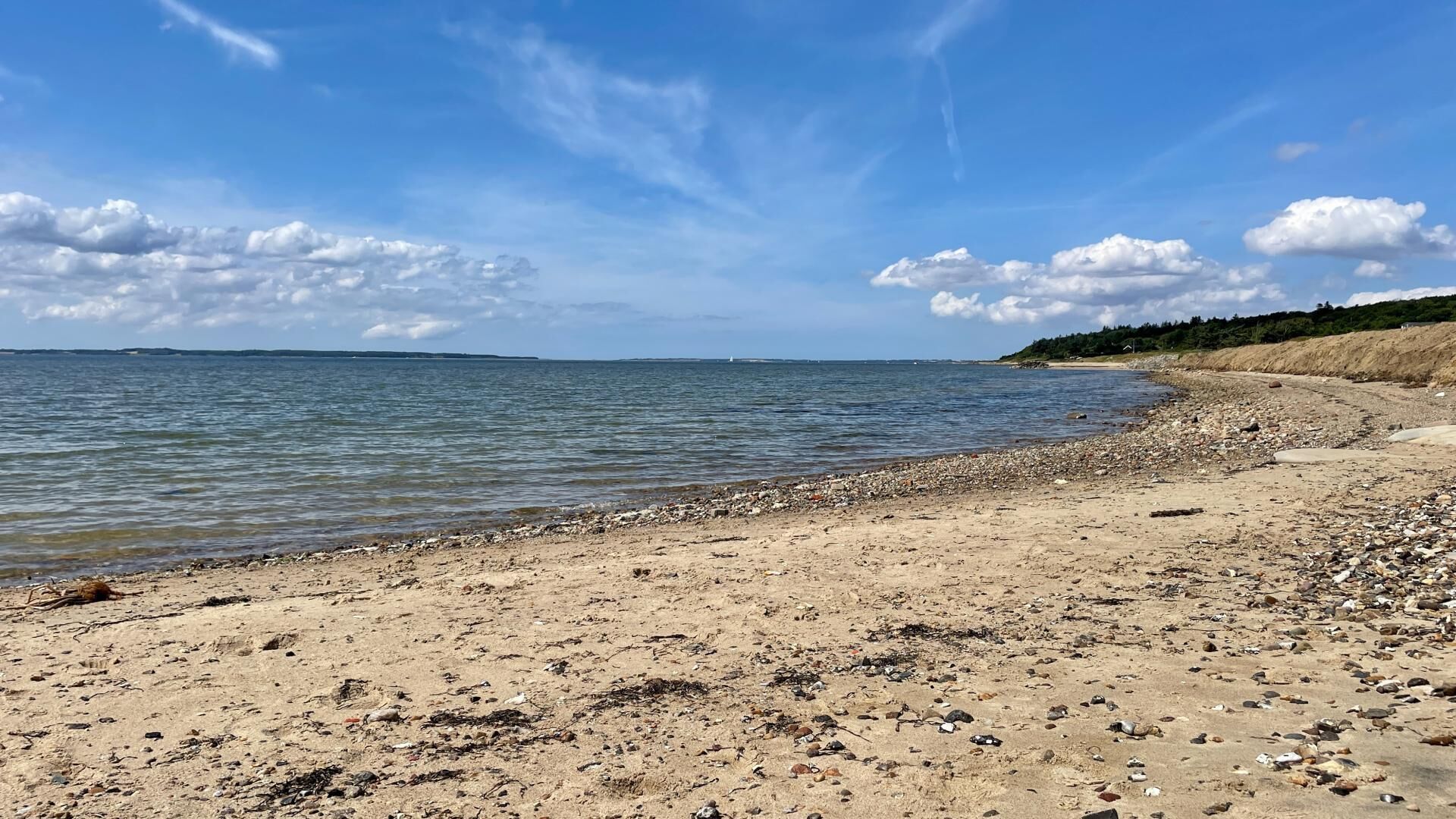 A beach with a rocky shoreline and calm water.