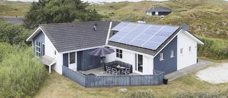 A house with a solar panel roof, a covered patio, and a fenced yard.