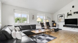A modern living room with a black leather sofa, a wooden coffee table, and a black TV stand. - VillaVilla 974 - Hvide Sande, Vestjylland (Hvide Sande)