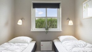A room with two beds, a window with a view of greenery, and wall-mounted lamps. - VillaVilla 974 - Hvide Sande, Vestjylland (Hvide Sande)