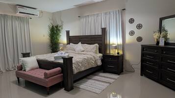 Une chambre à coucher avec un lit, des tables de chevet, une commode, une plante en pot et un miroir.