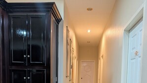 A hallway with a dark wooden cabinet, white doors, and framed pictures on the wall. - Delightful 3-bedroom house with AC in charming Cunupia (Cunupia)
