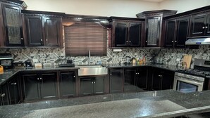 A kitchen with dark cabinetry, a stainless steel sink, and a built-in oven. - Delightful 3-bedroom house with AC in charming Cunupia (Cunupia)