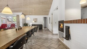 Un intérieur moderne avec une table à manger en bois, des chaises noires et des luminaires suspendus.