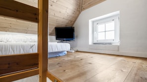 A room with a sloped ceiling, wooden flooring, a bed with white bedding, a television on a stand, and a window with a view. - VillaVilla 989 - Søndervig, Vestjylland (Ringkøbing)