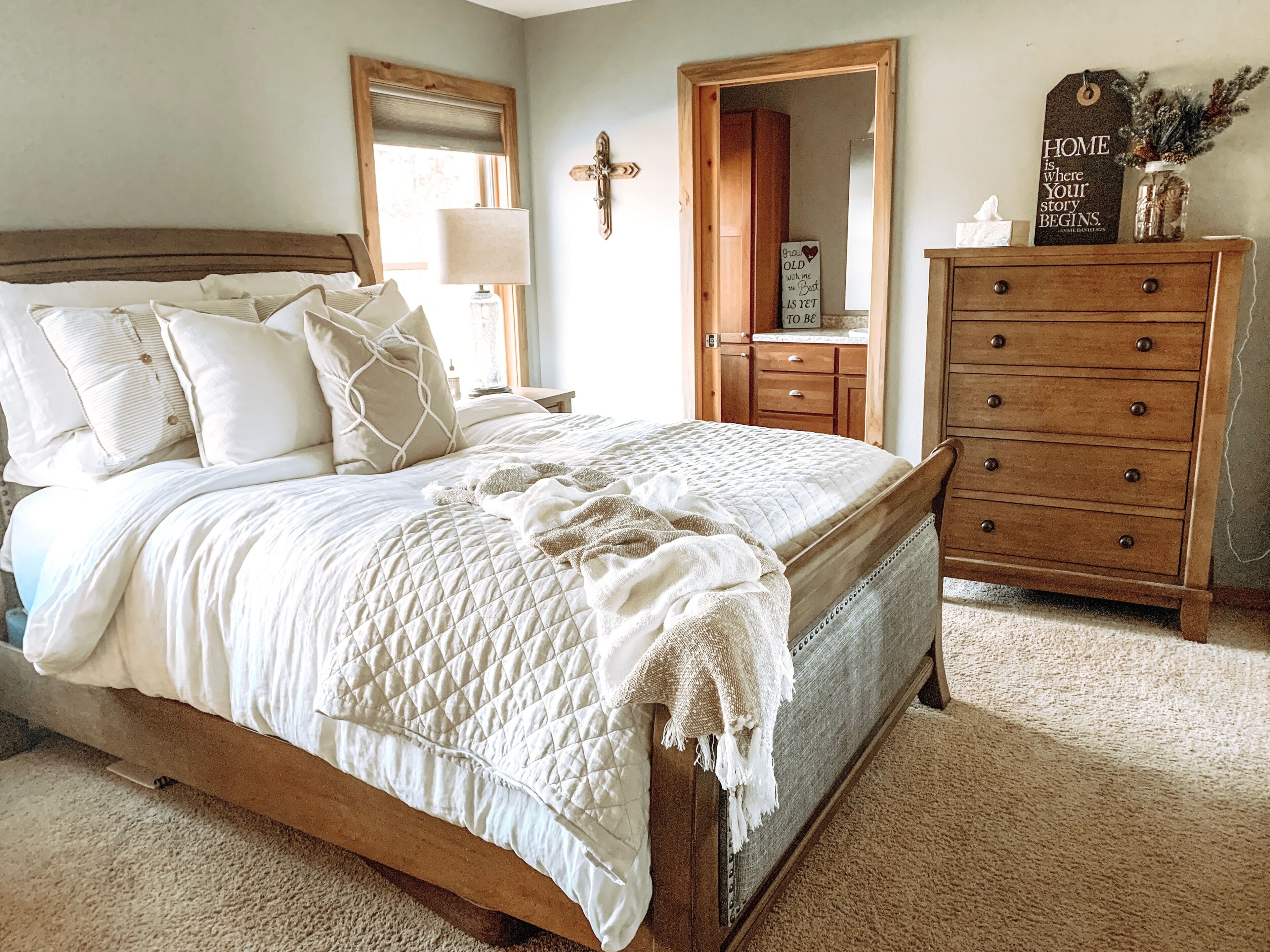 A bedroom with a wooden bed, a nightstand, a dresser, and a mirror.
