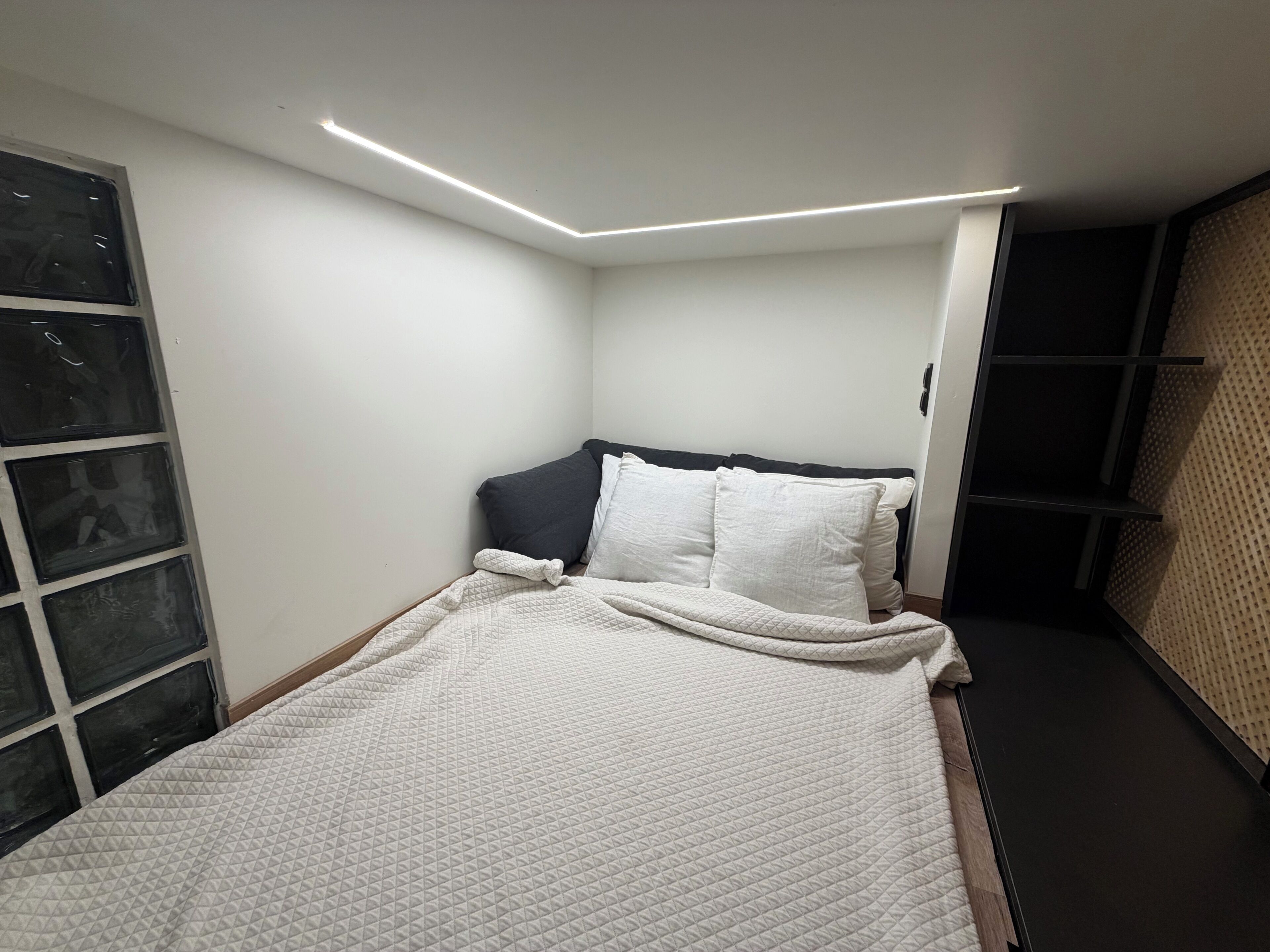 A bedroom with a bed, a headboard, and a window.
