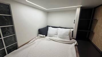 A bedroom with a bed, a headboard, and a window.