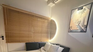 Een slaapkamer met een bed, nachtkastje en een wandgemonteerde airconditioning.