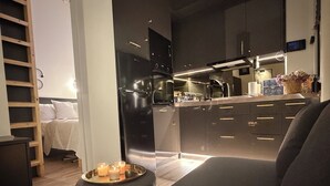 Een moderne keuken met een ingebouwde oven, een magnetron en een koffieapparaat. Op de voorgrond staat een klein, rond tafeltje met kaarsen.