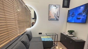 Een moderne woonkamer met een gebogen muur, een bank, een klein tafeltje met kaarsen en kunstwerken aan de muren.