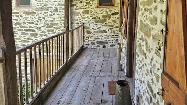 A stone building with a wooden balcony and a metal bucket. - La Viguerie - JOUQUEVIEL (JOUQUEVIEL)