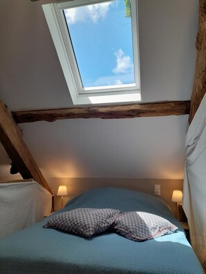 A bedroom with a skylight, a bed with a patterned pillow, and two bedside lamps. - La Viguerie - JOUQUEVIEL (JOUQUEVIEL)
