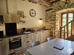 A kitchen with a built-in oven, a coffee maker, and a clock on the wall. - La Viguerie - JOUQUEVIEL (JOUQUEVIEL)