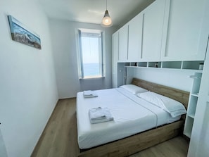 Ein Schlafzimmer mit einem Bett, einem Fenster und einem Bild an der Wand.