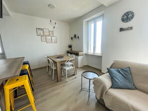 Una sala de estar moderna con un sofá, una mesita redonda y una zona de comedor con sillas y una mesa.