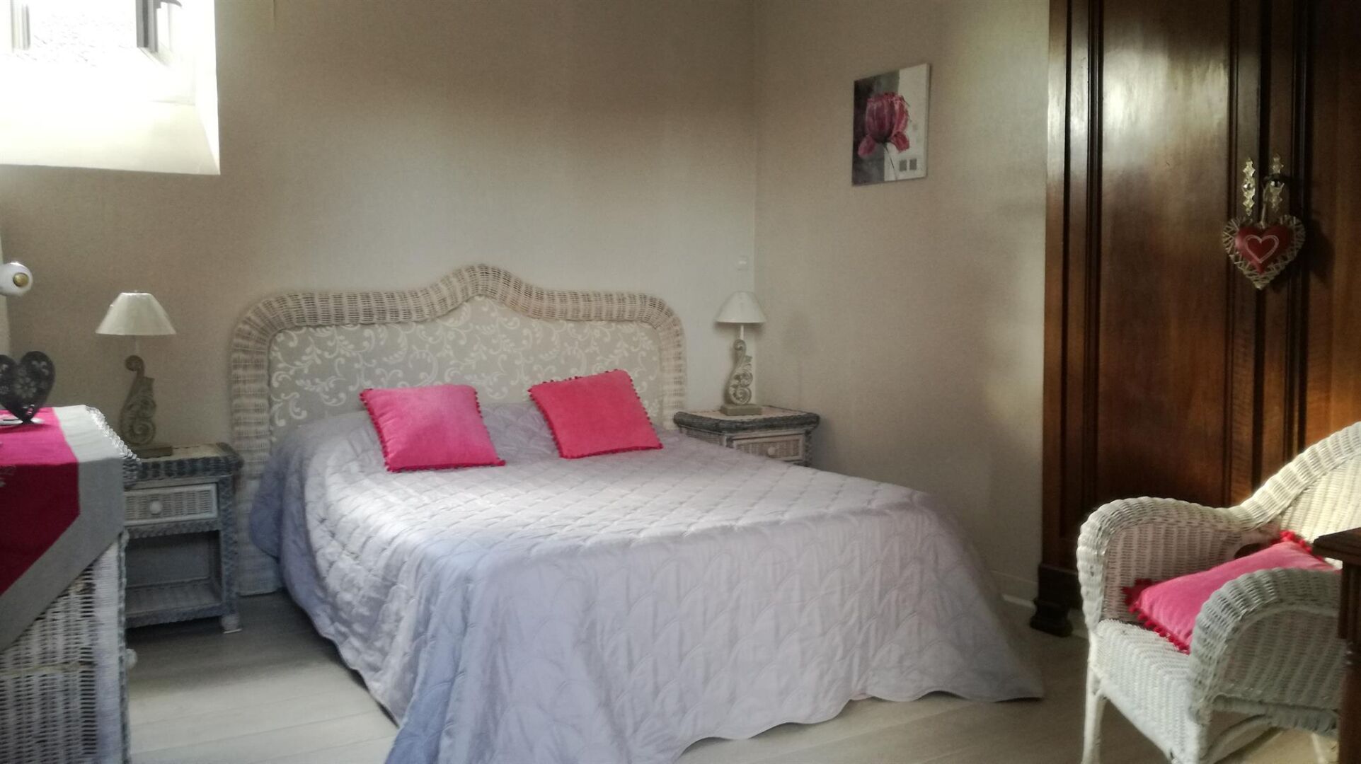 Une chambre à coucher avec un lit, deux tables de chevet, une chaise et un mur orné d’un tableau.