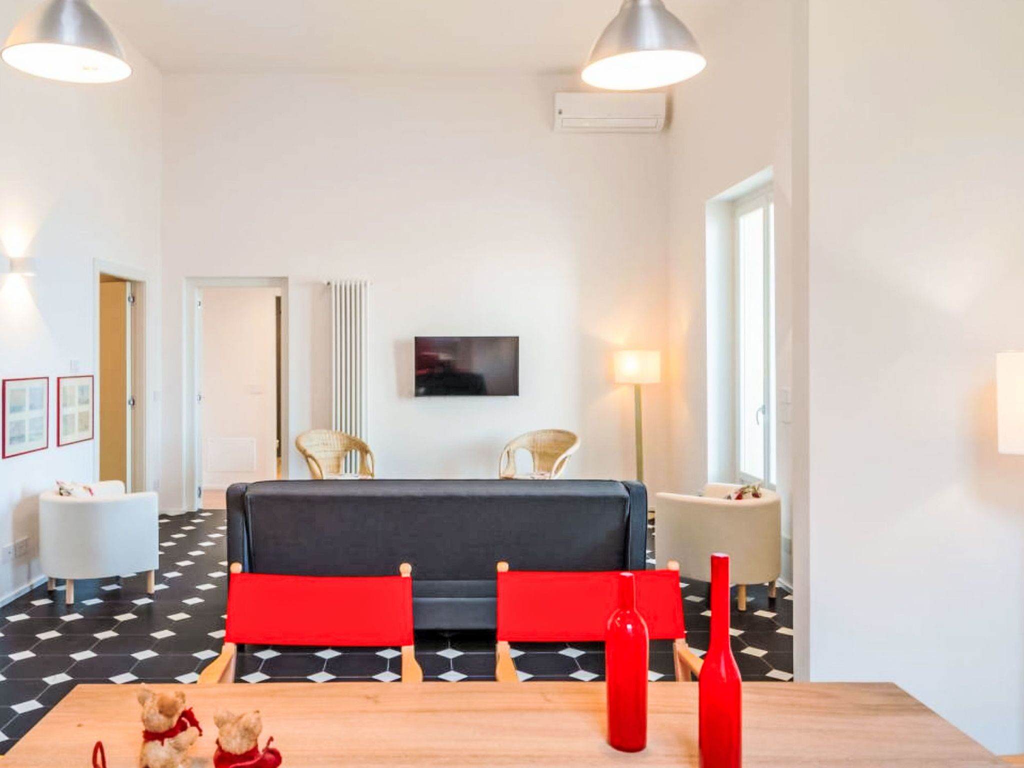 A modern room with a sofa, chairs, a table, and a television on the wall.