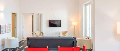 A modern room with a sofa, chairs, a table, and a television on the wall.