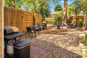 Une terrasse extérieure avec un barbecue, des sièges et une clôture en bois.
