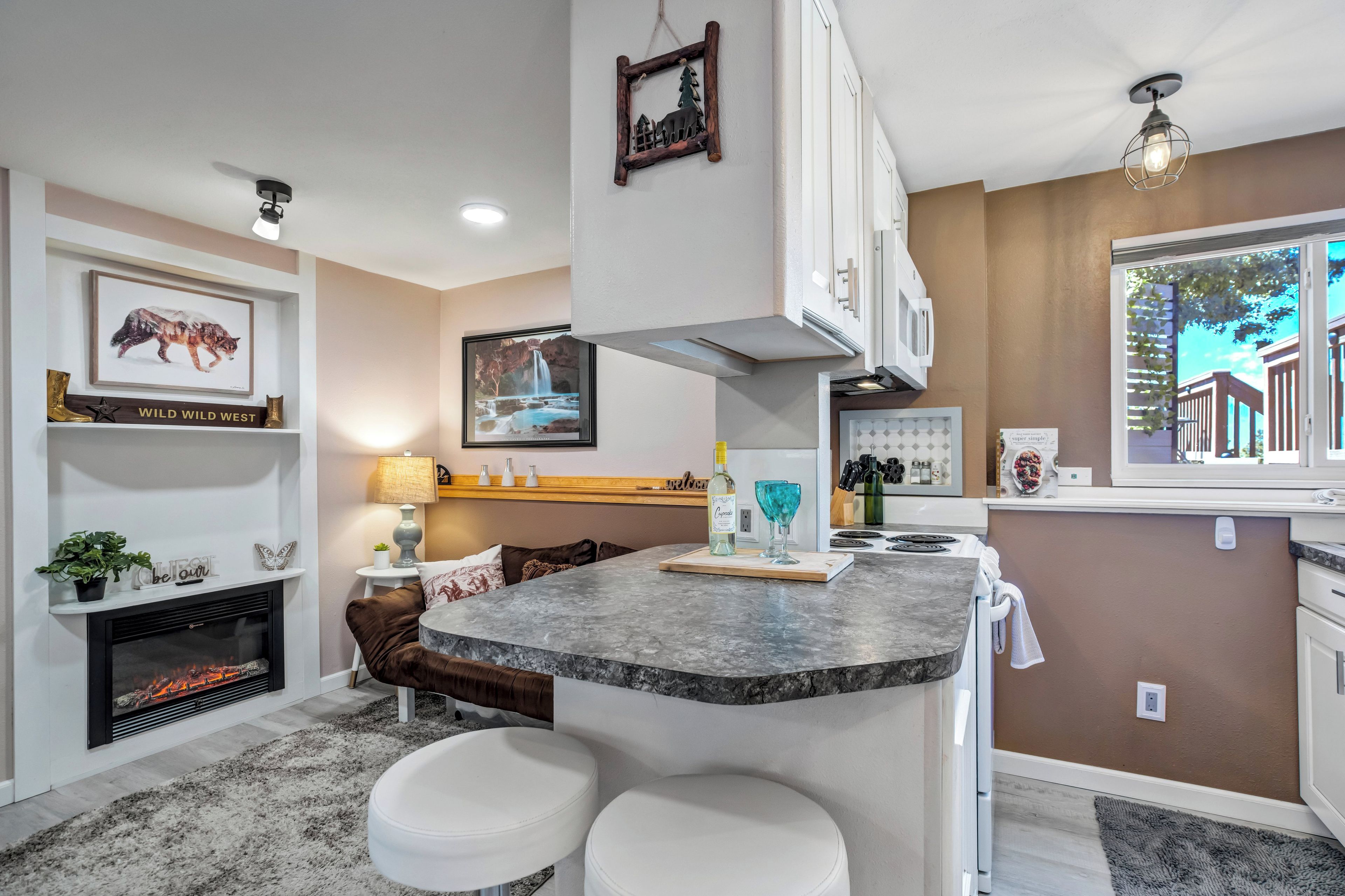 A modern kitchen with a marble island, white cabinetry, and a fireplace.