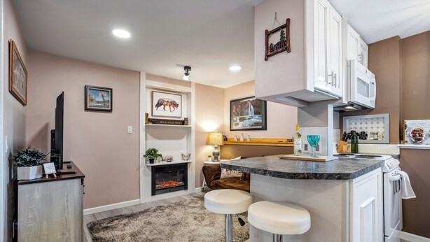 Een moderne keuken met een centraal eiland, barstoelen, een open haard en wanddecoratie.