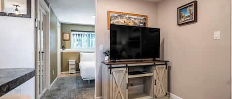 A hallway with a TV on a wooden stand, a framed picture on the wall, and a carpeted floor.