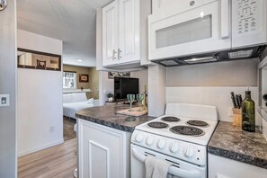 Une cuisine moderne avec des meubles blancs, un four à micro-ondes encastré et une cuisinière à gaz.